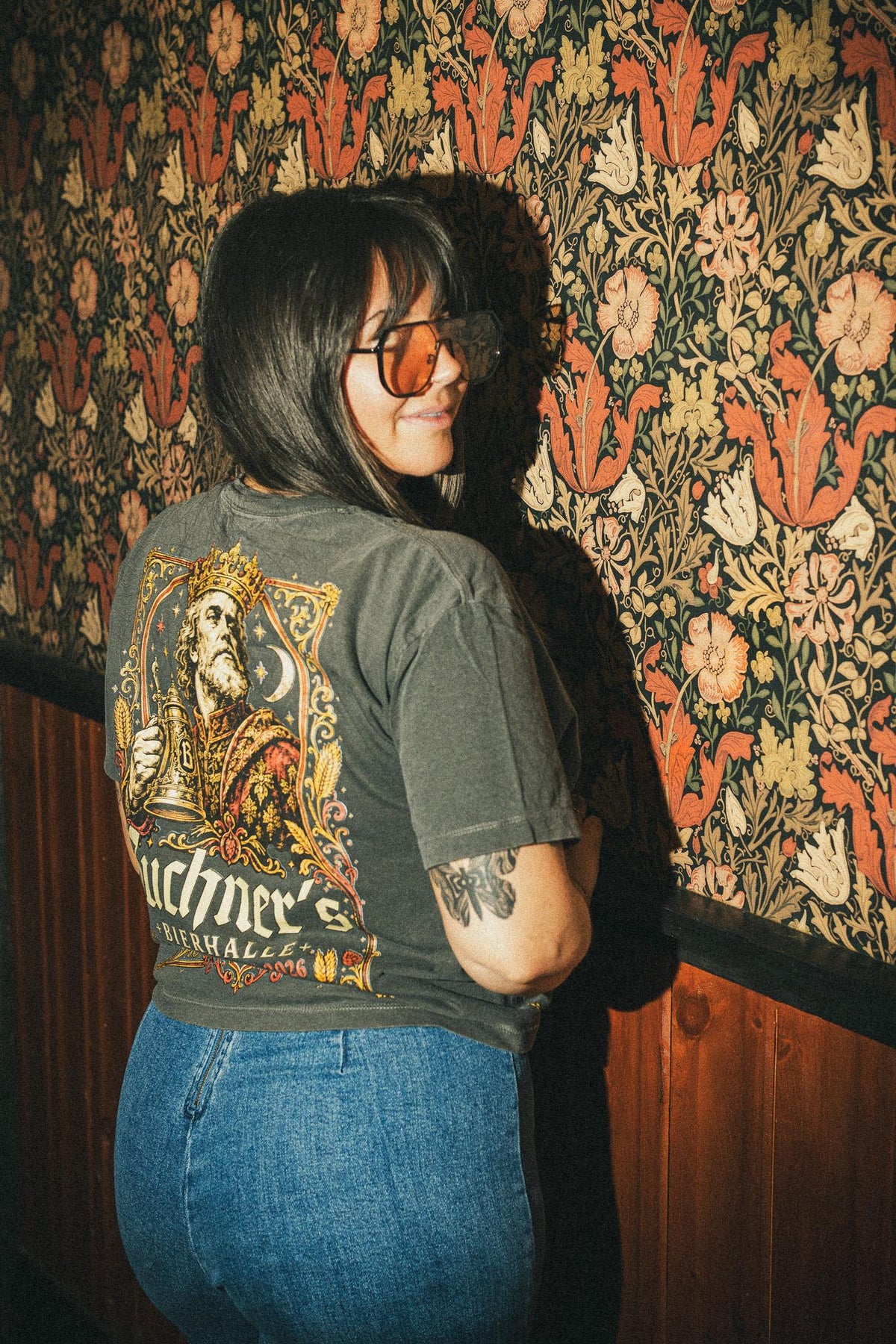 Customer modeling a charcoal Buchner's Oktoberfest 2026 graphic T-shirt inside Buchner's Bierhalle