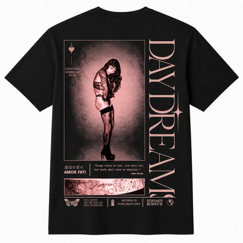 A black short-sleeve t-shirt shown from the back, featuring a large graphic print with a woman in a pink-toned portrait, vertical text reading 'DAYDREAM', and smaller decorative text and illustration elements.